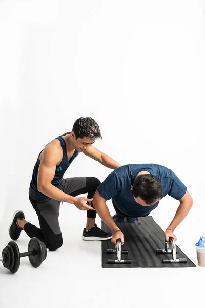 Entrenador acompaña a un hombre haciendo ejercicios push-up con herramientas —  Fotos de Stock