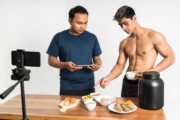 Twee gezondheid en sport blogger met vinger wijzen gezonde voeding menu terwijl houden kopje drank en tablet — Stockfoto