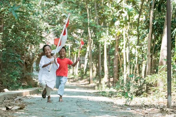 Dois meninos correr quando segurando a bandeira vermelha e branca e levantou a bandeira — Fotografia de Stock