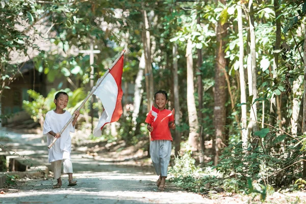 Twee jongens die de rode en witte vlag vasthouden en de vlag hijsen — Stockfoto