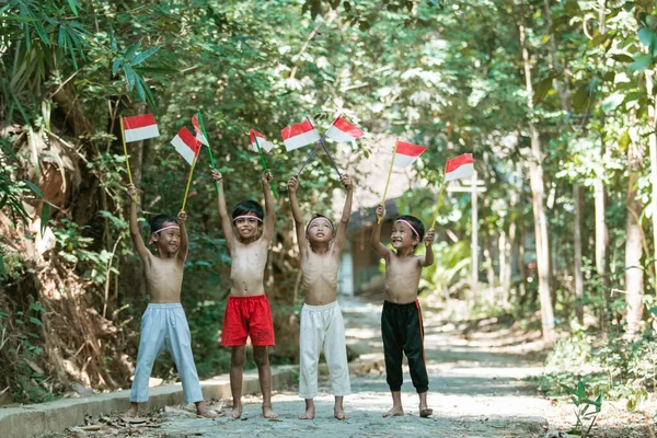 Het hebben van plezier groep van kinderen staan zonder kleren bij het vasthouden van kleine de rode en witte vlag — Stockfoto