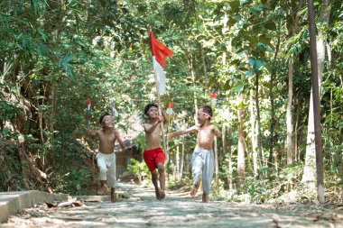 Üç Asyalı çıplak koşuyor kırmızı ve beyaz bayrağı tutarken birbirlerini kovalıyorlar.