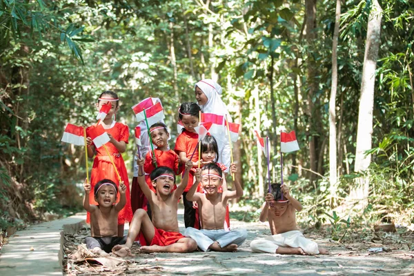 Groep kinderen met kleine rode en witte vlag die samen worden gehesen — Stockfoto