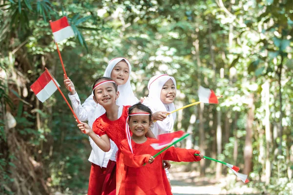 Memiliki kelompok menyenangkan gadis-gadis kecil asia memegang bendera merah dan putih dan mengangkat bersama-sama bendera — Stok Foto