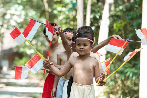 Het hebben van leuke groep kinderen lopen zonder kleren bij het vasthouden van kleine de rode en witte vlag — Stockfoto