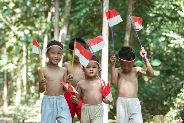 Sekelompok anak-anak berjalan memegang bendera merah dan putih kecil bersama-sama — Stok Foto