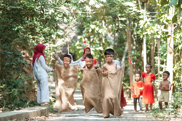Indonesische kinderen proberen te springen en rennen op zak race met vrienden ondersteunen op het dorp — Stockfoto