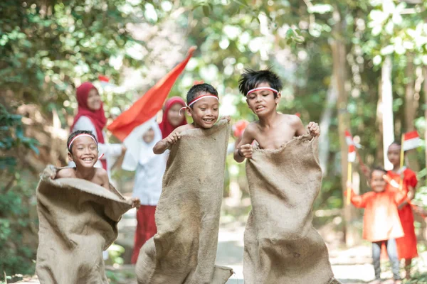 Drie aziatische kinderen concurreren om de voorhoede van de zak race — Stockfoto