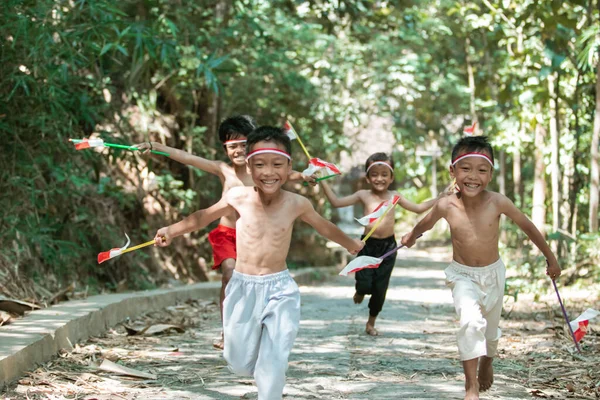 Met plezier groep van aziatische kleine jongens lopen zonder kleren jagen elkaar wanneer het houden van kleine de rode en witte vlag — Stockfoto