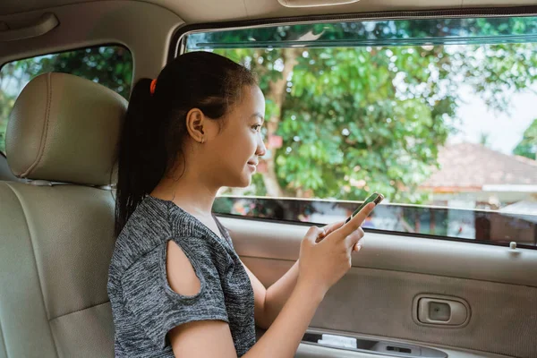 Menina asiática sorrir quando segurando um telefone enquanto sentado no carro — Fotografia de Stock