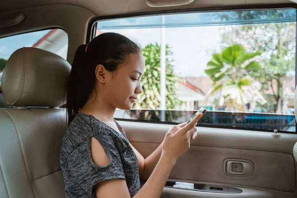 Teenage girl using a smartphone and look to screen while sitting in the car — Stock Photo, Image