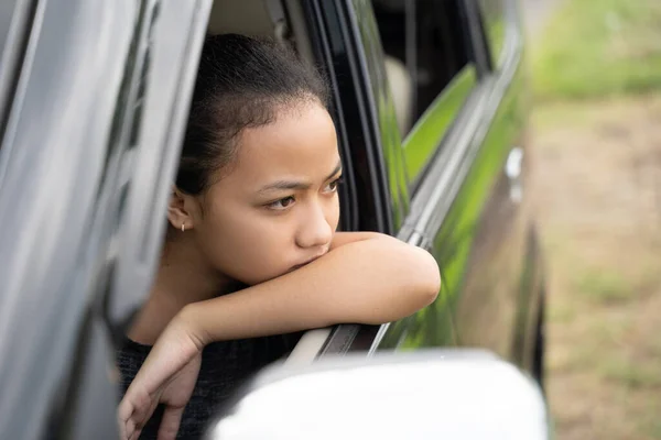 The sad teenage girl looks outside while sitting in the car with the windows open — Stock Photo, Image