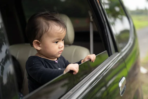 窓を開けて車の中に立ちながら外を見る可愛い赤ちゃん — ストック写真
