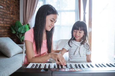 Bir çocuk, kız kardeşinin eşlik ettiği bir müzik aleti çalmayı öğrenir.