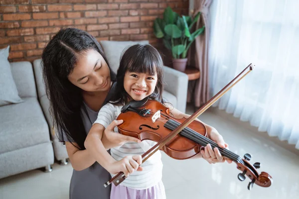 小女孩微笑着，就像少女帮助孩子正确地握住小提琴一样 — 图库照片