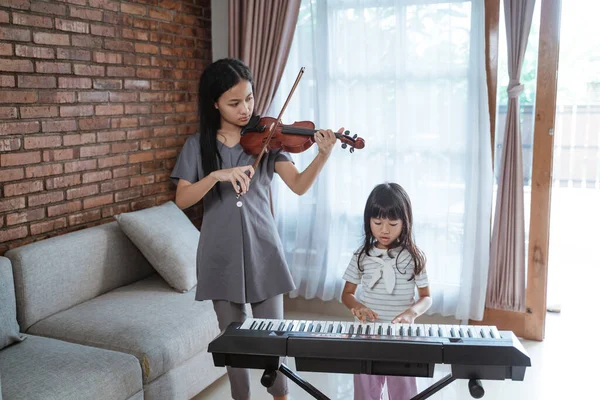 小女孩和姐姐一起拉小提琴，弹奏乐器钢琴 — 图库照片