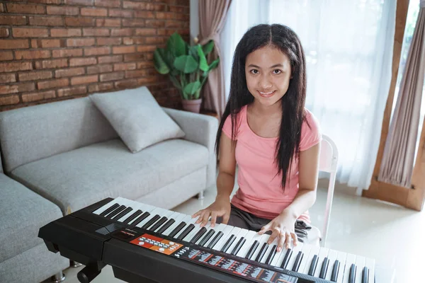 Tonårstjej i rosa kläder lär sig att spela piano när man sitter — Stockfoto