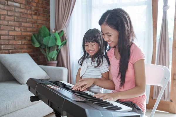 两个亚洲姐妹坐在一起弹钢琴，玩得很开心 — 图库照片