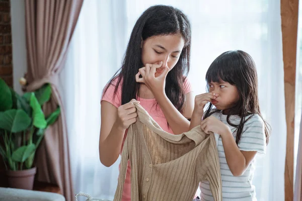 Close-up van twee aziatische zusters gesloten zijn neus door zijn vinger bij het houden van een geur kleding — Stockfoto