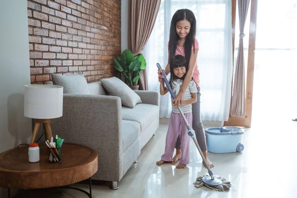 Happiness of the two sisters while doing household chores — Stock Photo, Image