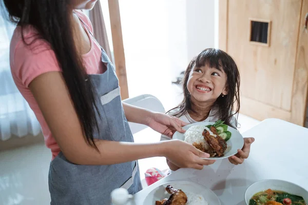 Gros plan d'une excitée petite fille asiatique recevoir une assiette de nourriture tout en étant assis — Photo