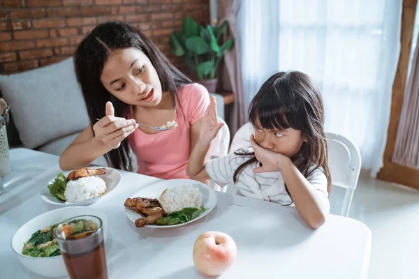 Gadis kecil Asia menutupi mulutnya sebagai kakaknya memberi makan makanannya — Stok Foto