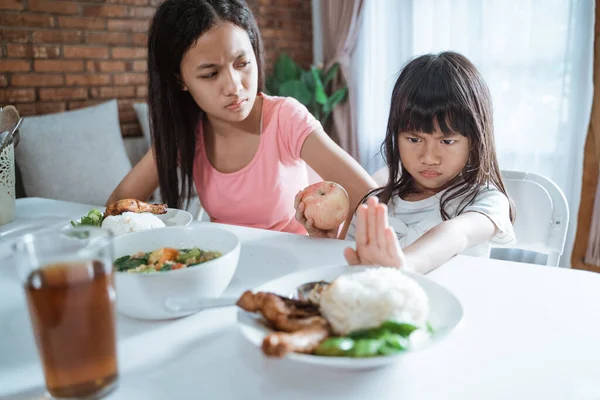 Niña se niega a comer arroz vegetal porque elegir manzana y su hermana mayor está molesta —  Fotos de Stock