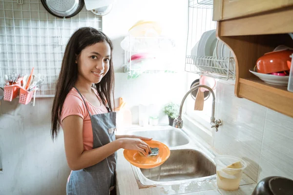 Adolescentes felizmente hacen las tareas domésticas lavando platos haciendo actividades —  Fotos de Stock