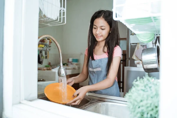 Retrato de chica adolescente asiática haciendo tareas domésticas lavando platos en fregadero de cocina — Foto de Stock