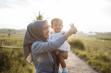 Peçeli anne, kızını yolda tutarken oyun oynuyor.