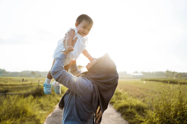 Gesluierde moeder gooit zijn dochter als staande de weg in het midden van de rijstvelden — Stockfoto