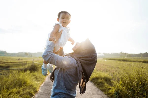 Asiática madre criando a su hija cuando de pie la carretera en medio de los campos de arroz —  Fotos de Stock