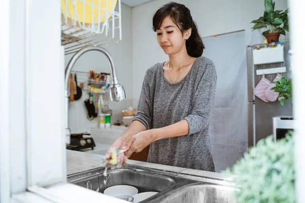 Mulher lavar os pratos na cozinha — Fotografia de Stock