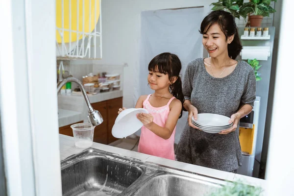 Pequeña niña ayudar a su madre en lavar platos — Foto de Stock