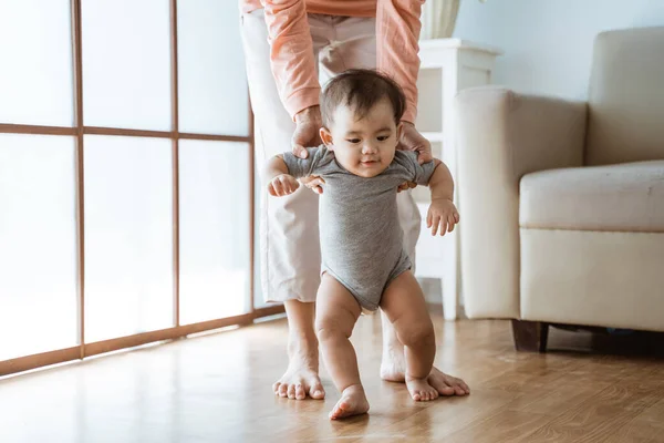 Madre ayudar a su bebé a caminar su primer paso — Foto de Stock