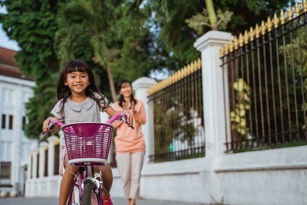 Un portrait d'une petite fille joyeuse et heureuse jouant un vélo dans le parc — Photo
