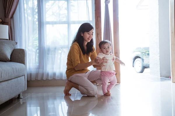 Madre ayudar a su bebé a caminar su primer paso — Foto de Stock