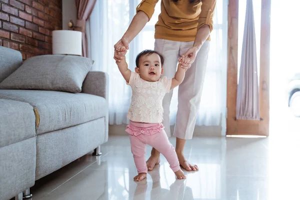 Madre ayudar a su bebé a caminar su primer paso — Foto de Stock