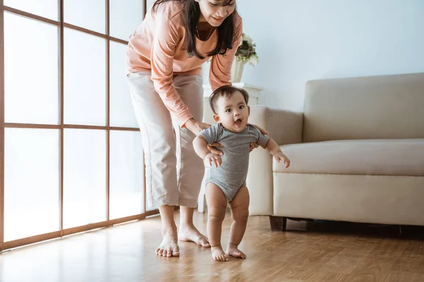 Madre ayudar a su bebé a caminar su primer paso — Foto de Stock