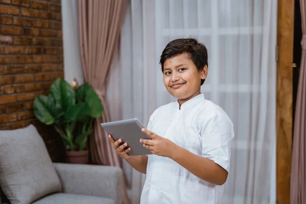 A smiling boy holding a tablet is standing — Stock Photo, Image