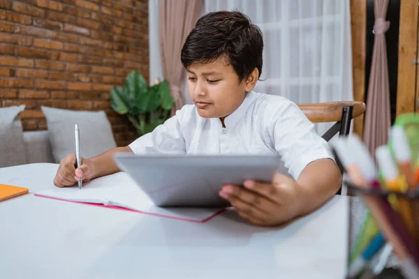 Partial view of smiling boy using digital tablet while sitting at desk — Stock Photo, Image