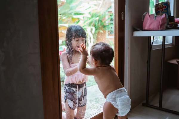 La hermanita se quedó mirando a su hermana mayor por la puerta de cristal. —  Fotos de Stock