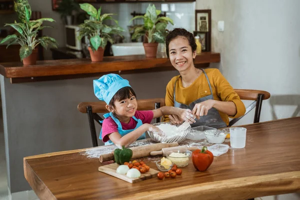 Mãe e pequena menina bonito em roupas chef fazendo pizza caseira — Fotografia de Stock