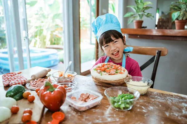 Улыбающаяся молодая девушка с пиццей на столе — стоковое фото
