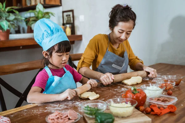 Güzel anne ve tatlı kızı birlikte merdane kullanıyorlar. — Stok fotoğraf