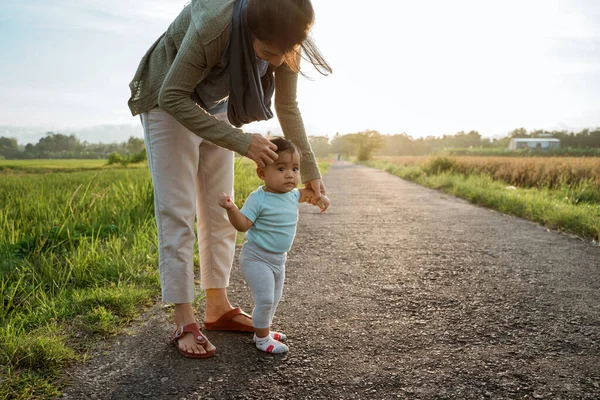 Madre aiutare il suo bambino a camminare il suo primo passo — Foto Stock