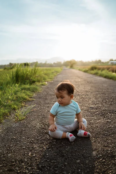 Adorável asiático bebê sentado sozinho no vazio estrada — Fotografia de Stock