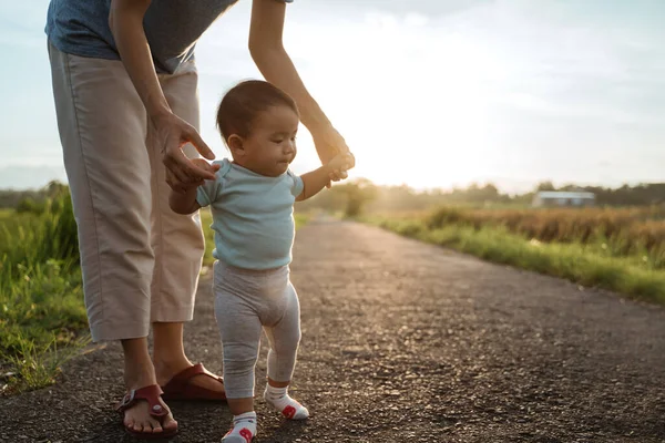 Madre ayudar a su bebé a caminar su primer paso — Foto de Stock