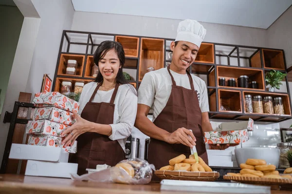 Parejas jóvenes haciendo rosquillas de panadería en la cocina — Foto de Stock