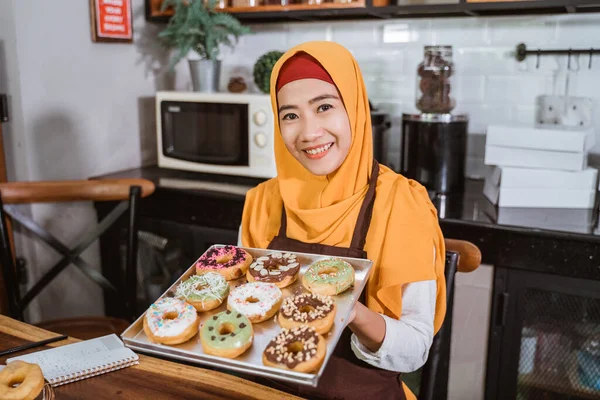 Gülümseyen kapüşonlu bir kadın bir kutu ev yapımı çörek taşıyor. — Stok fotoğraf